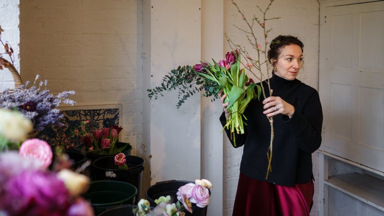 Leanne Smith holds a branch of foliage in the flower shop of Munstead Wood